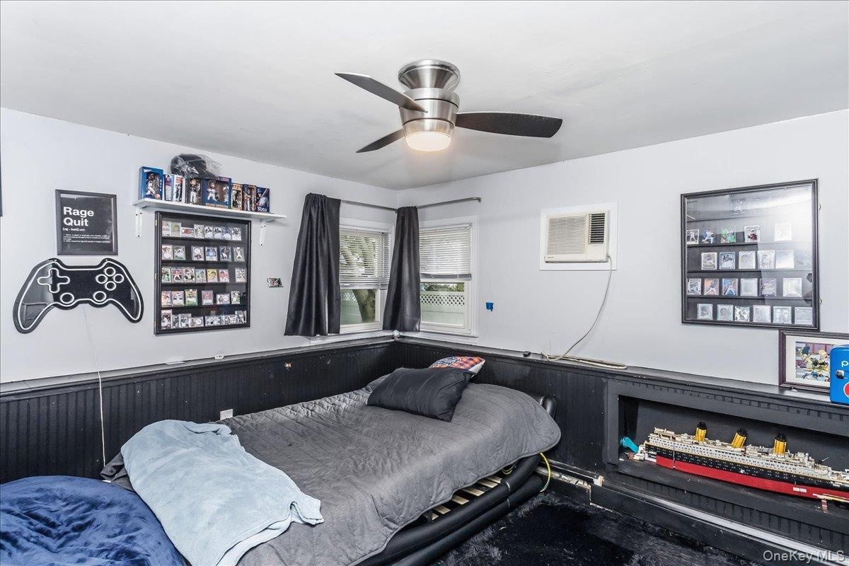 Room featuring a ceiling fan with integrated lighting, white walls, and dark wainscoting