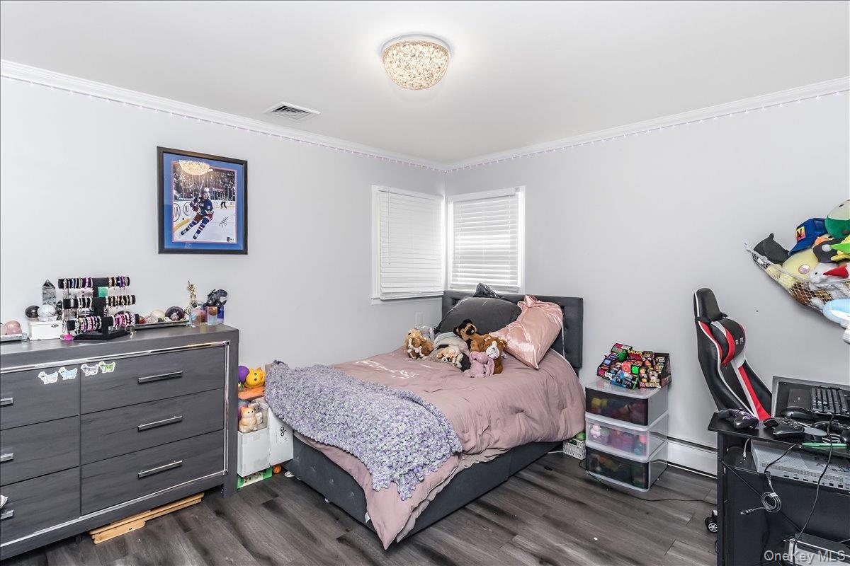 Room featuring wood-finish flooring, white walls, and crown molding