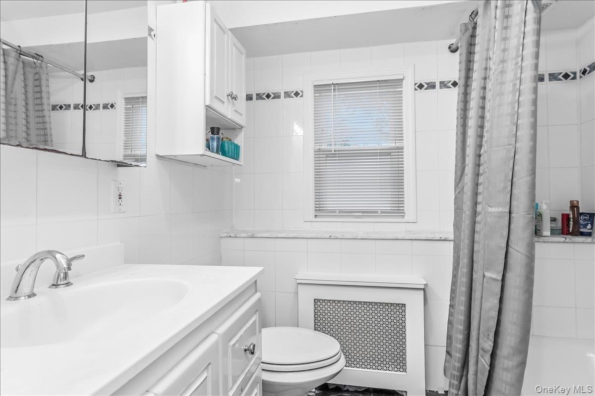 Bathroom featuring white tiled walls, a white vanity with integrated sink, and a chrome faucet