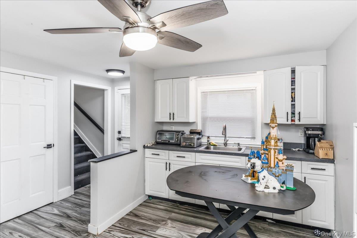 Modern kitchen area featuring white cabinetry, dark countertops, and wood-finish flooring