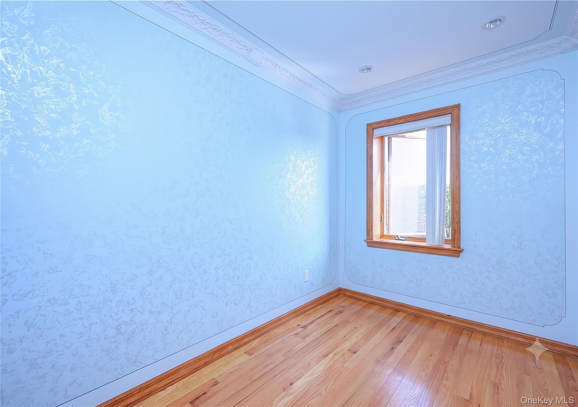 Hardwood flooring throughout featuring decorative wall finish and crown molding