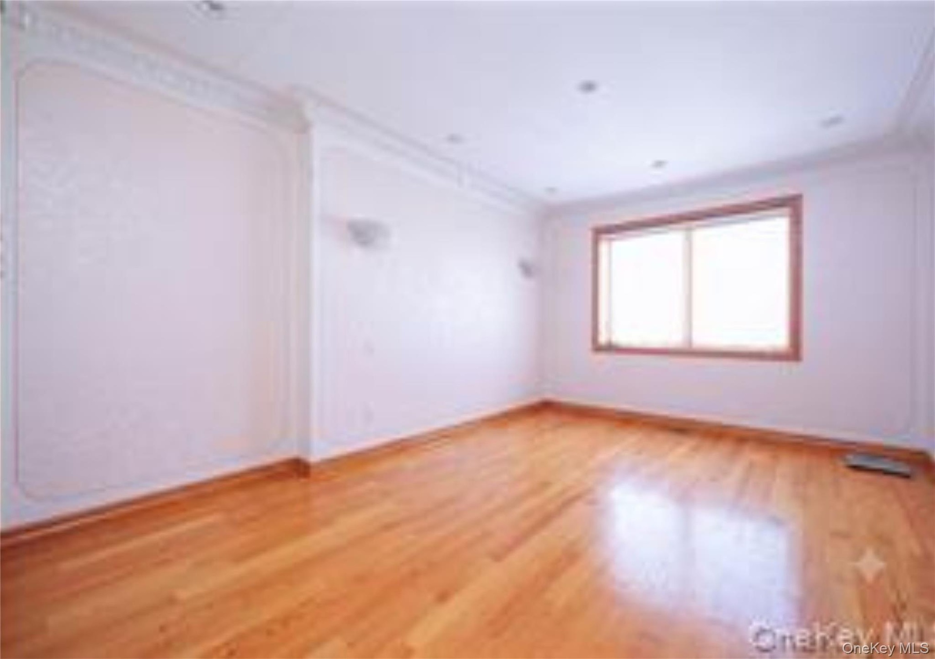 Spacious interior room featuring wood-finish flooring, recessed lighting, and decorative wall molding