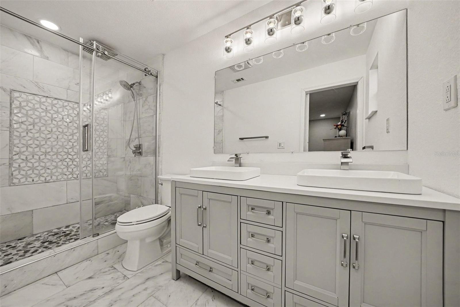 Primary Bath w/Marble tiled walk-in shower, marble tiled flooring and vanity w/ double sinks