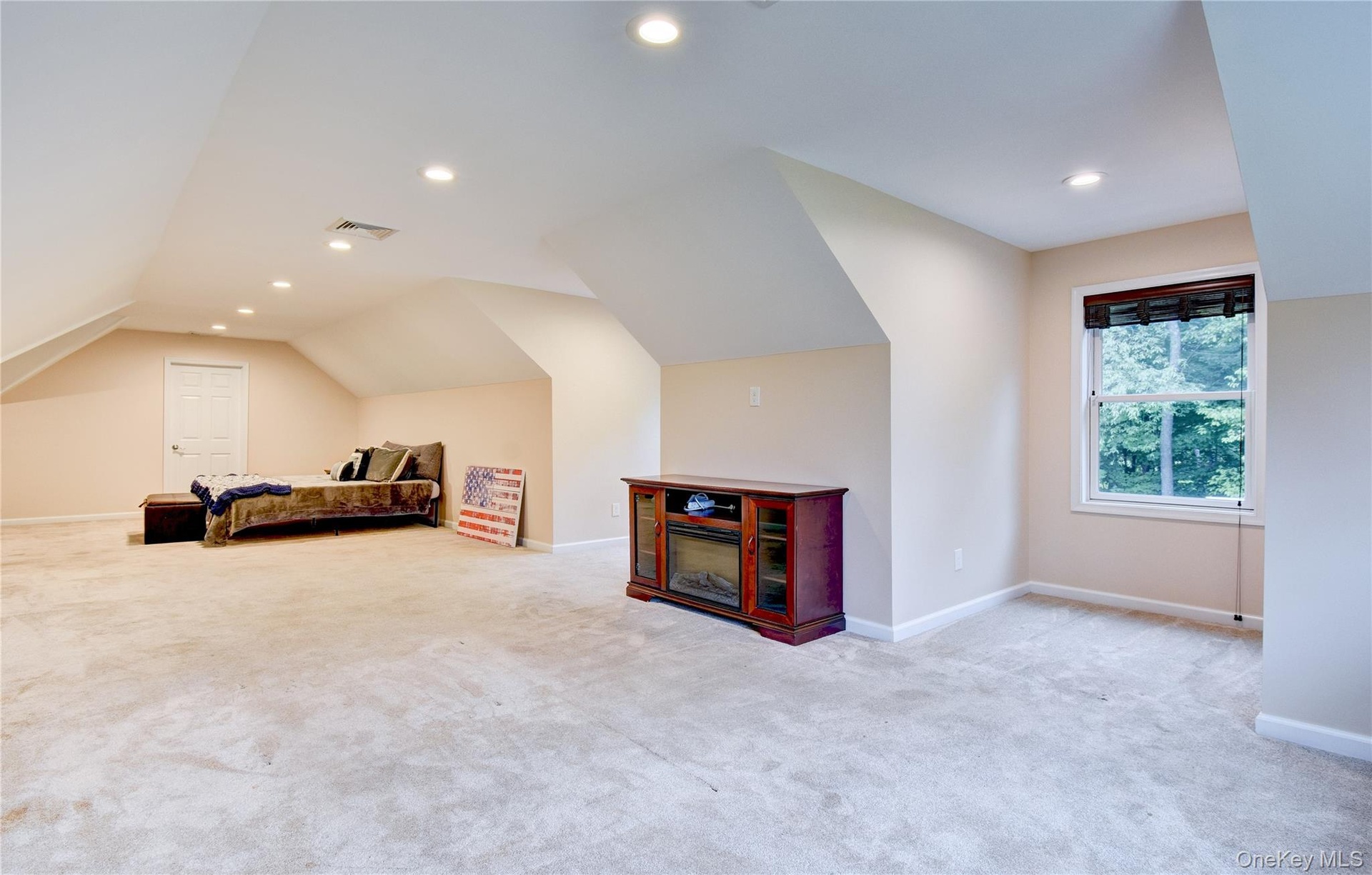 Spacious bonus room featuring vaulted ceilings, recessed lighting, neutral wall tones, light-colored carpeting, and a window with exterior tree views