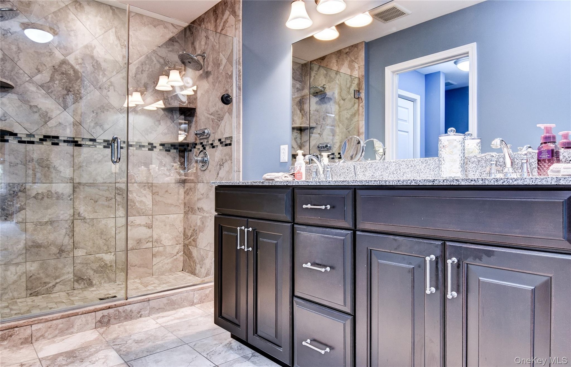 Primary Bathroom featuring a dual vanity with dark wood cabinetry, granite countertop, and two undermount sinks