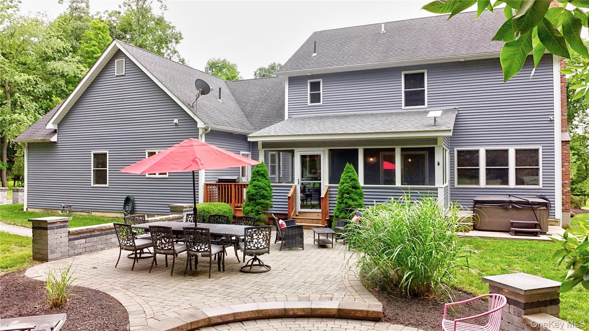 Expansive paver patio with a stone wall, offering direct access to the screened porch and a dedicated space for outdoor entertaining