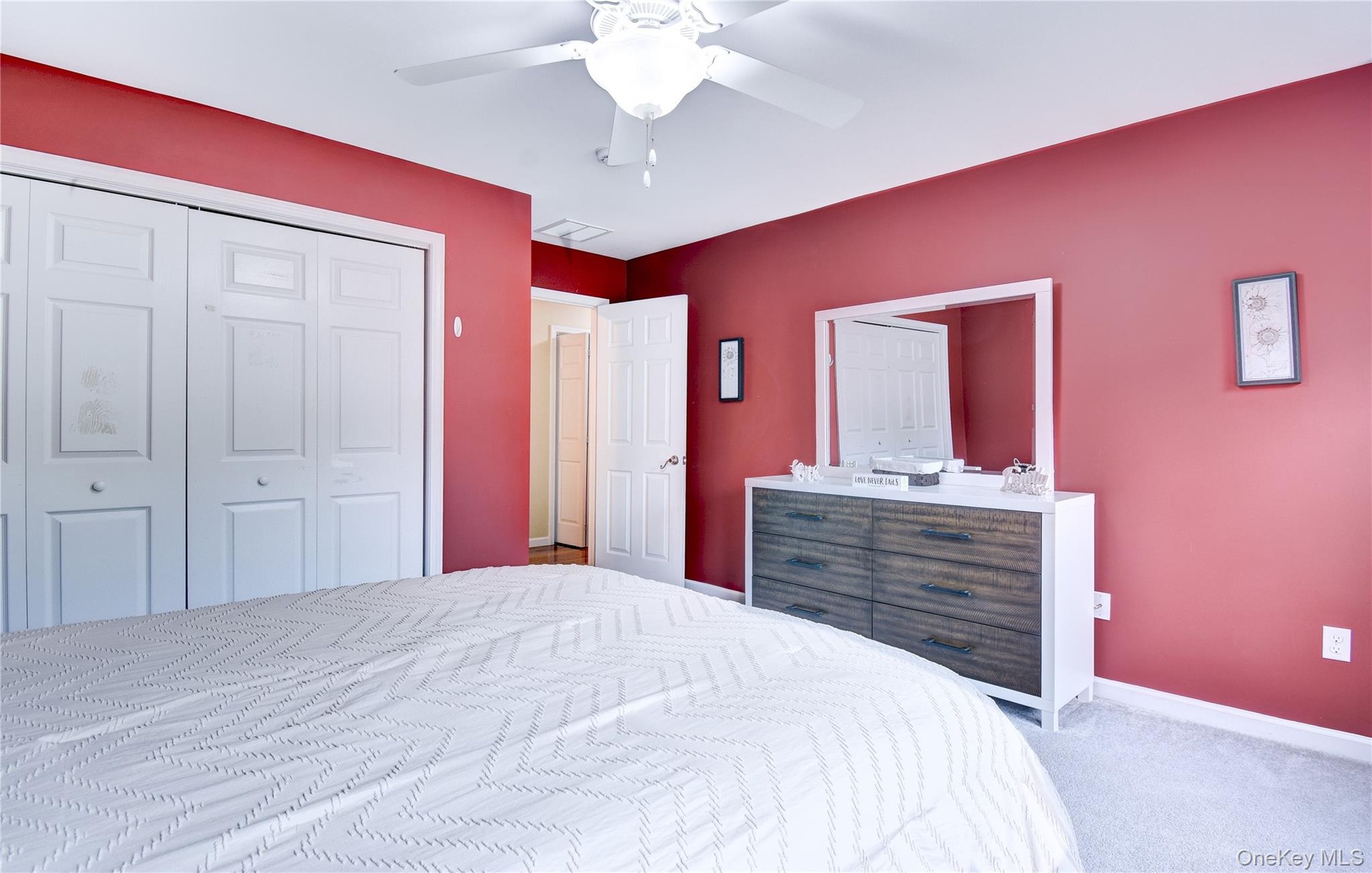 Bedroom featuring neutral-toned carpet, a ceiling fan with integrated lighting, and white bi-fold closet doors