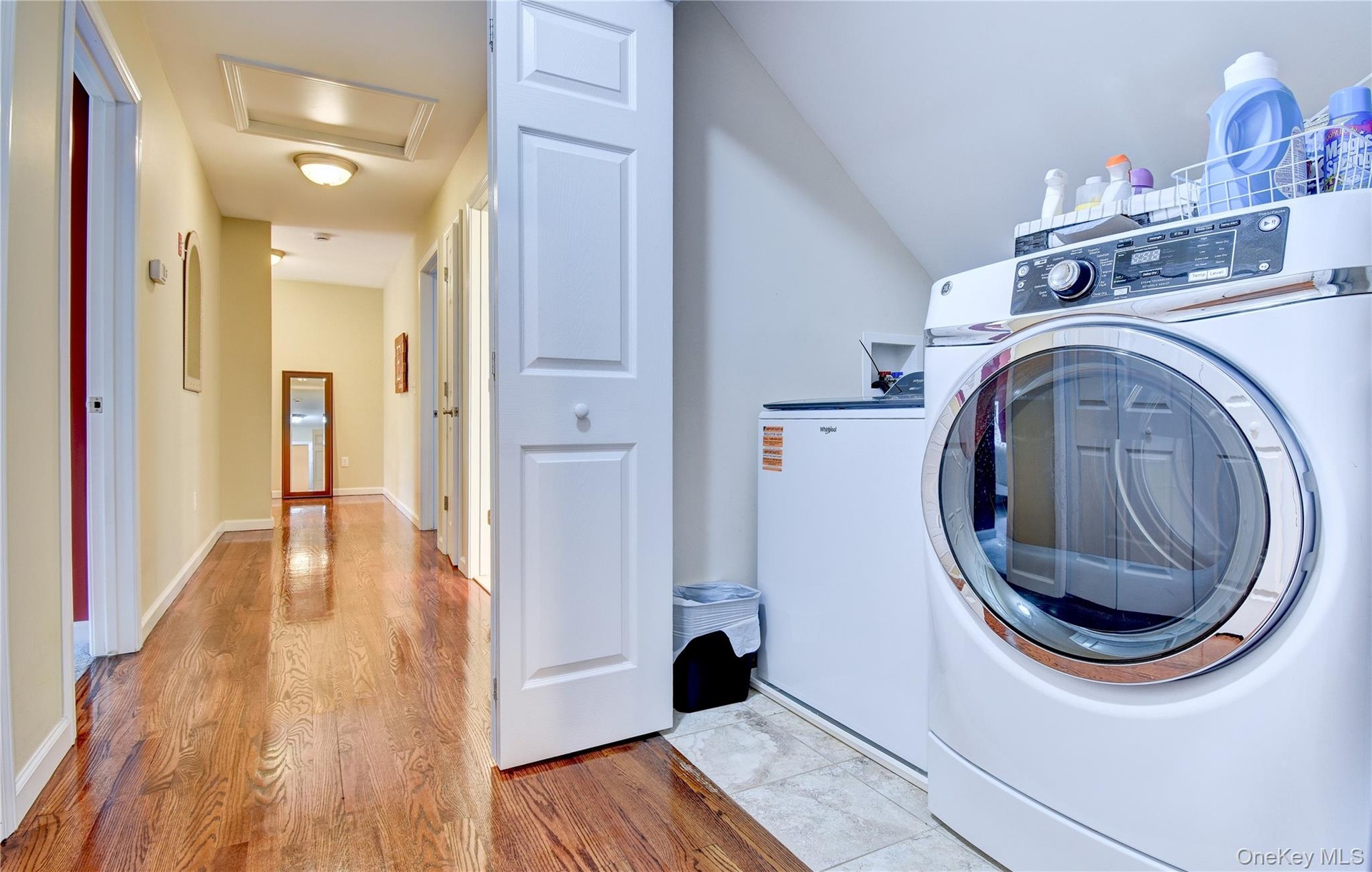 Dedicated laundry area with a front-loading washer and a top-loading appliance, featuring tiled flooring