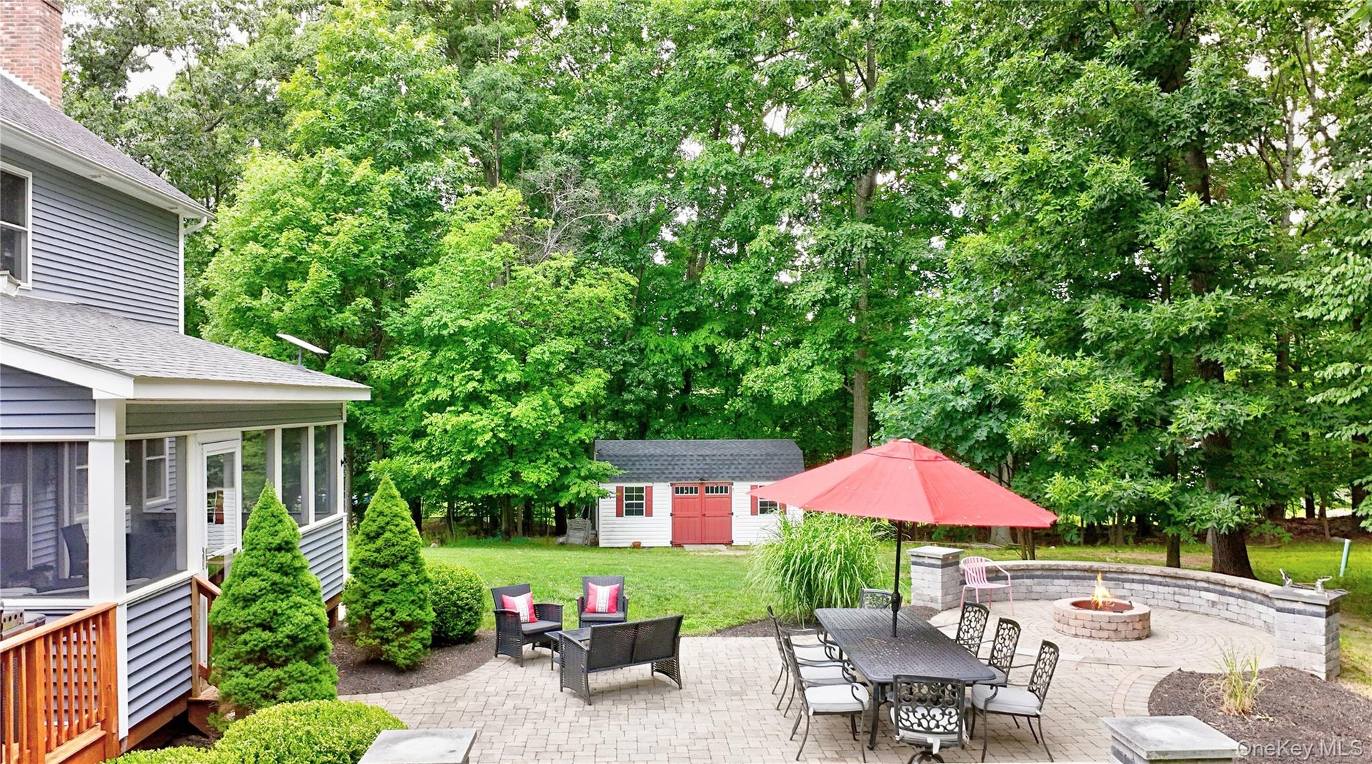 Expansive paver patio with a built-in fire pit and a stone retaining wall