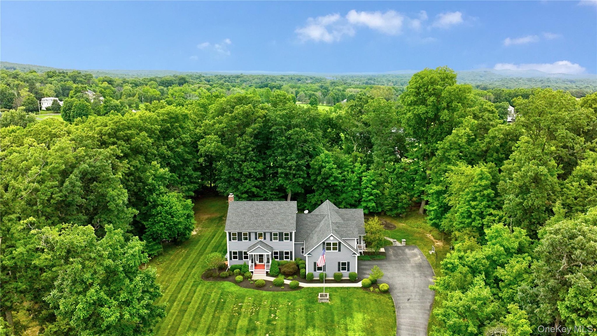 Expansive property featuring a grey siding residence with multiple dormers, black louvered shutters and with legal accessory apartment