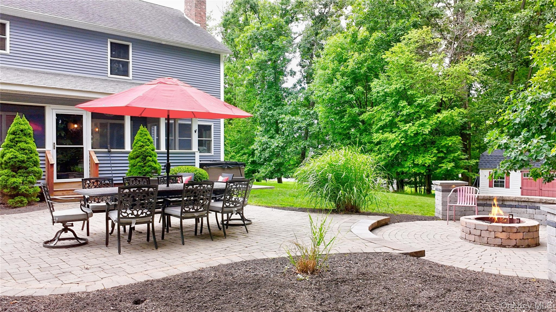 Expansive paver patio featuring a built-in fire pit, multiple seating areas, and direct access to the home