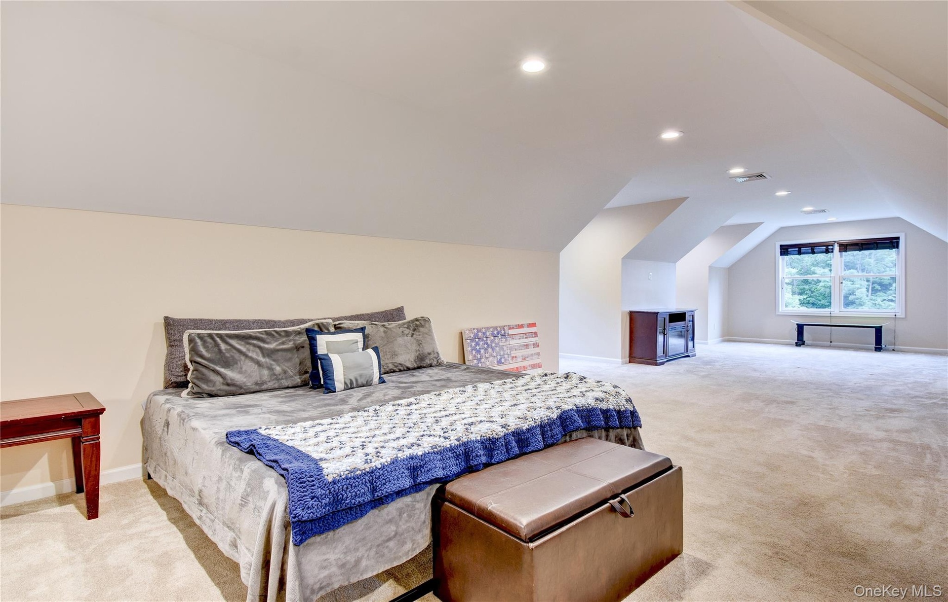 Spacious bonus room featuring sloped ceilings, recessed lighting, neutral-toned carpeting, and a double window