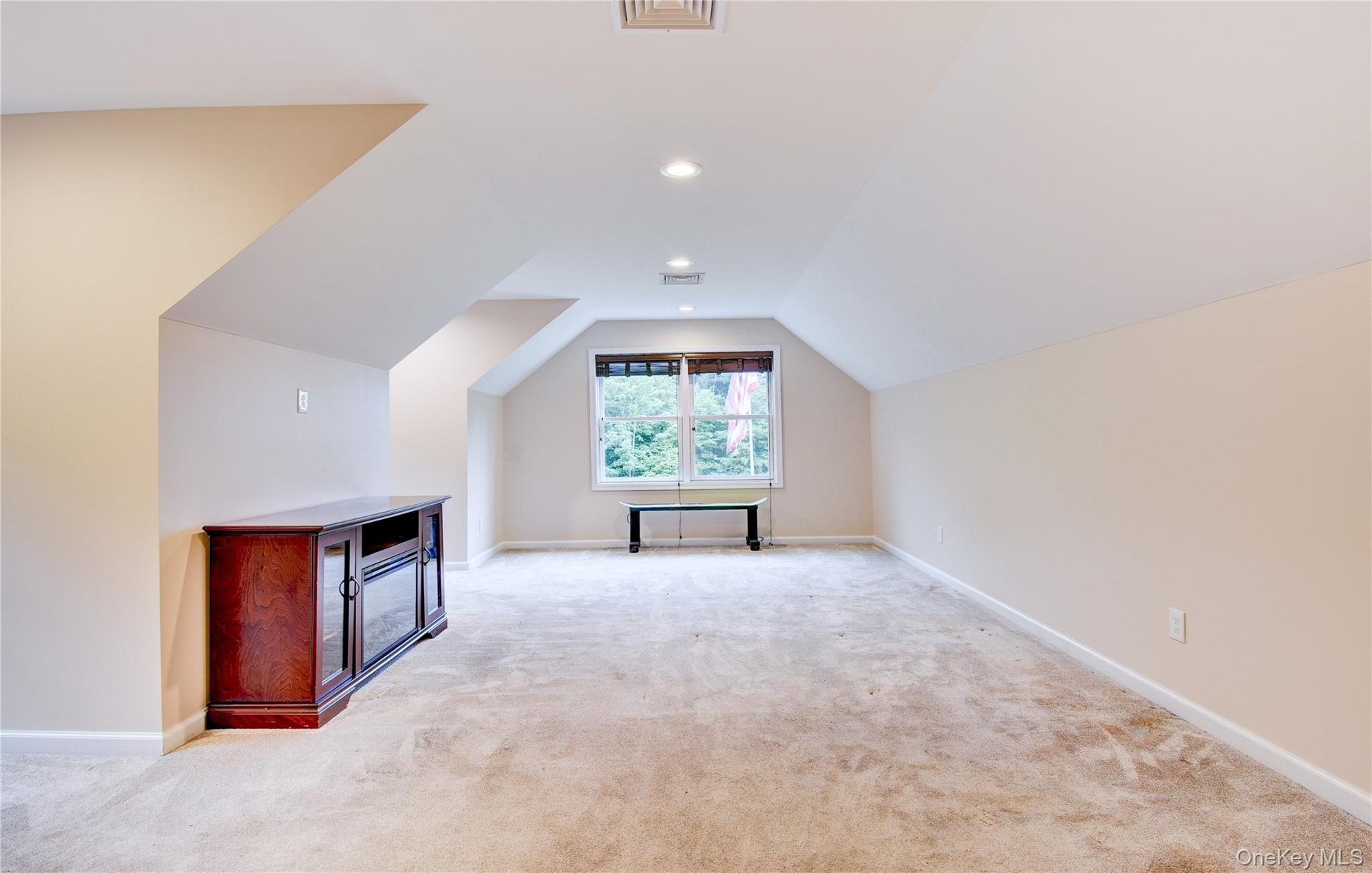 Spacious bonus room featuring sloped ceilings, recessed lighting, a window with exterior visibility, and light-toned carpeting
