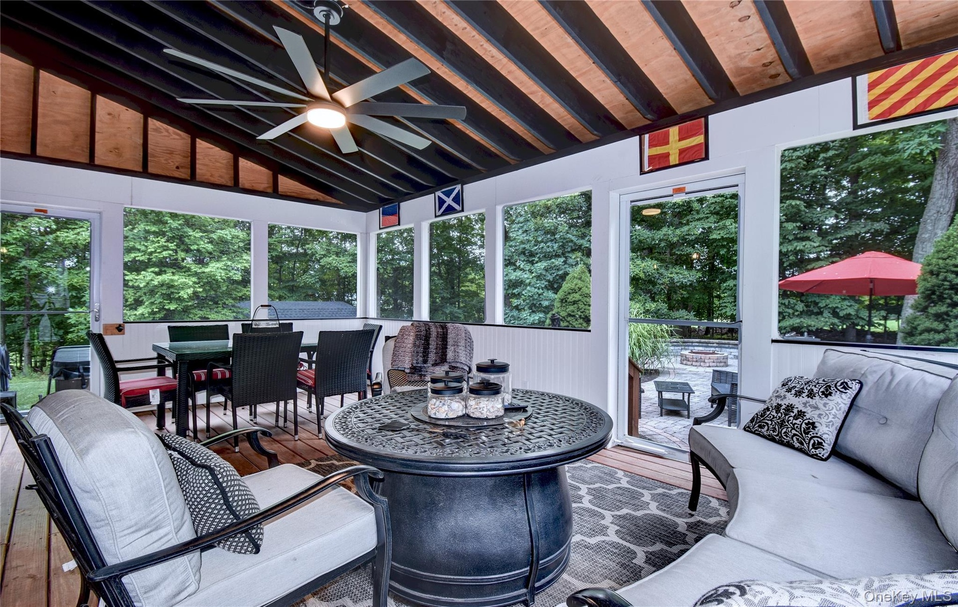 Screened porch featuring a vaulted ceiling with exposed beams, wood-finish flooring, and a ceiling fan