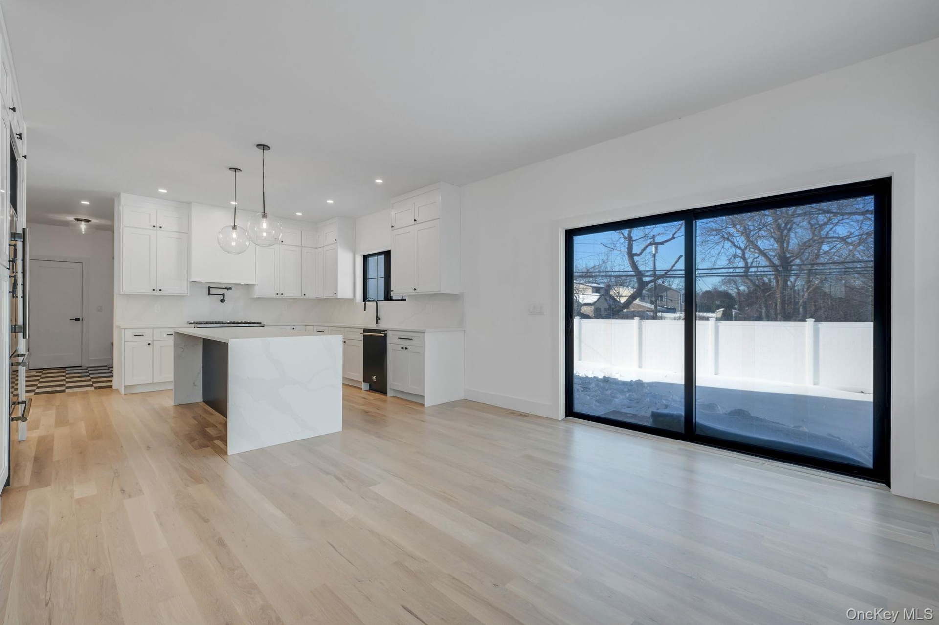 Bright dining space positioned beside kitchen and living room featuring wet bar and large glass sliders, offering great natural light and easy access 