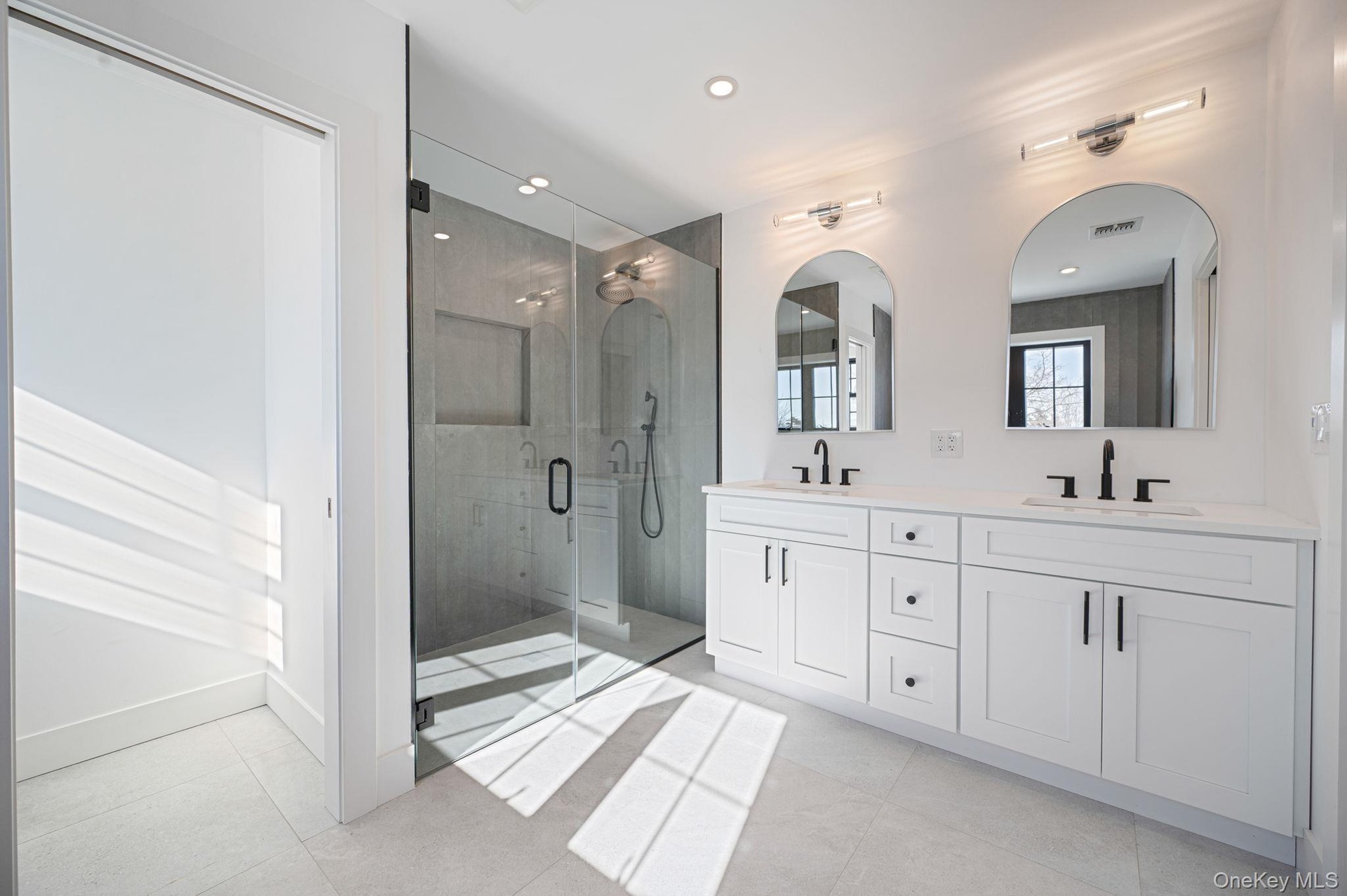 Spa like primary bath featuring a freestanding soaking tub, oversized glass shower, and modern finishes.