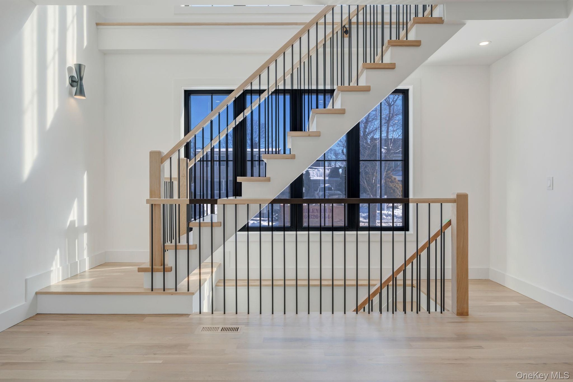 Striking staircase with modern railing and large window wall that brings light into both levels and adds architectural character.