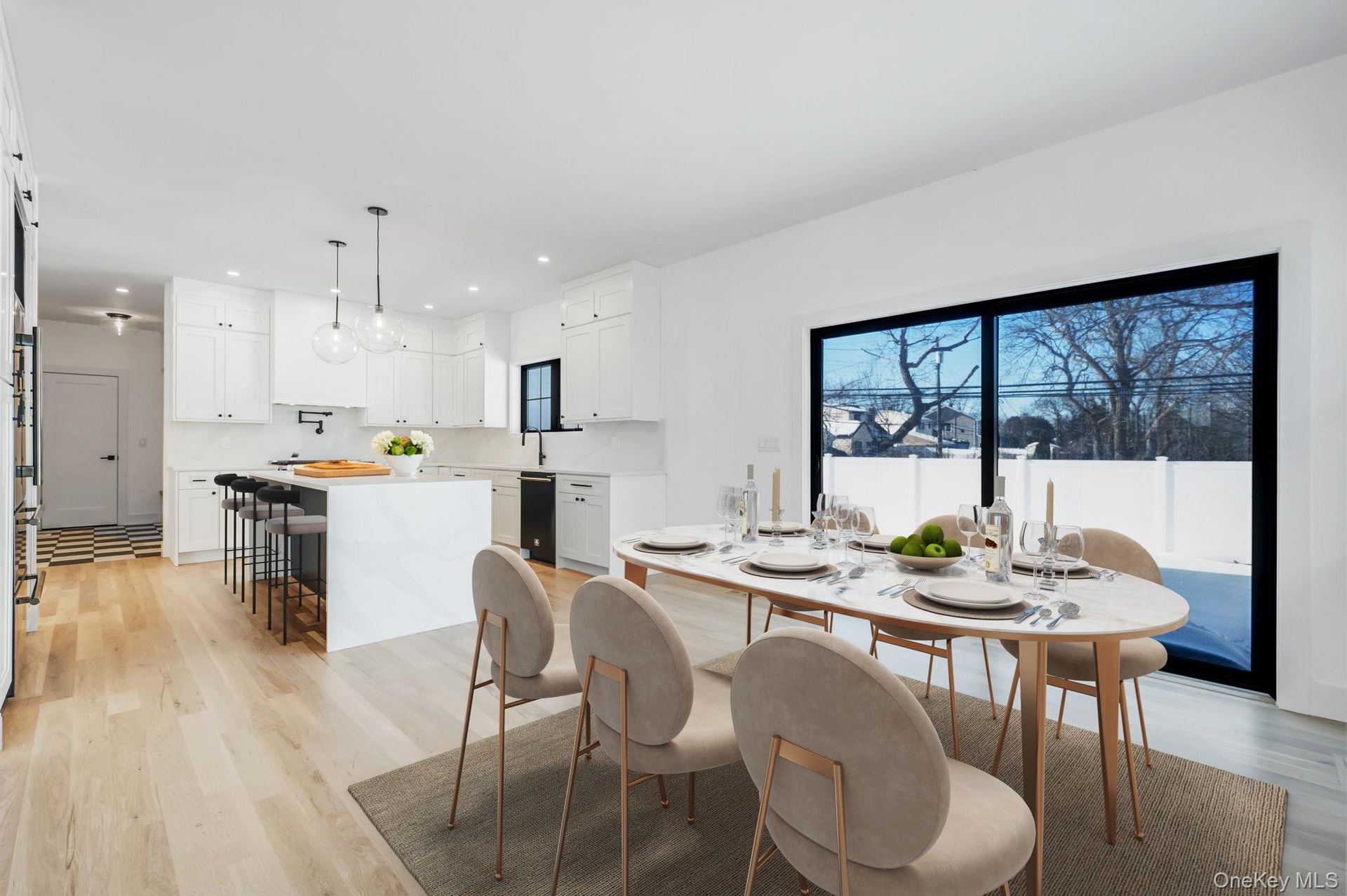 Bright dining space positioned beside kitchen and living room featuring wet bar and large glass sliders, offering great natural light and easy access 