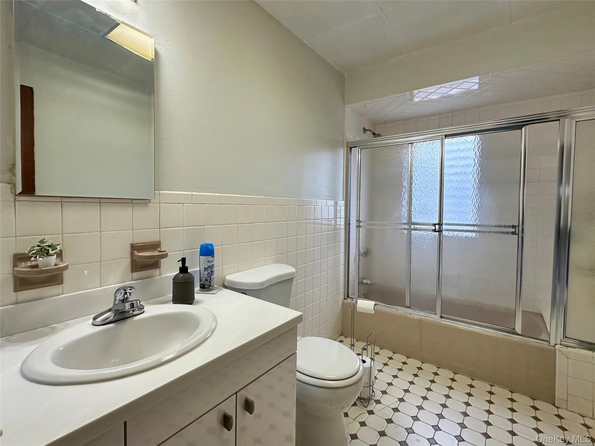 Bathroom featuring tiled shower / bath, vanity, and tile walls