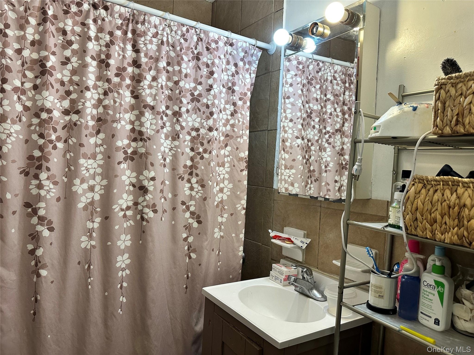 Bathroom featuring a shower with shower curtain, vanity, and tile walls