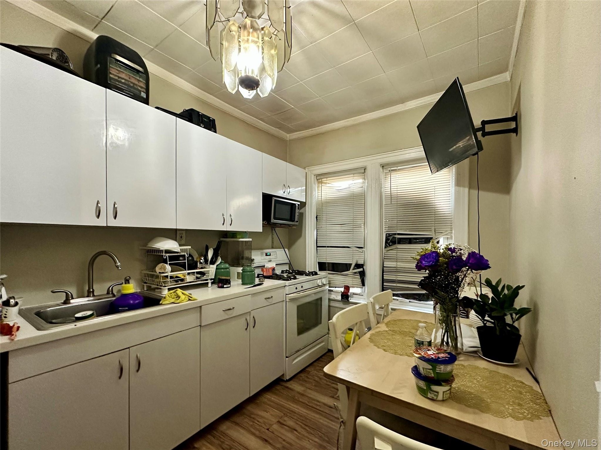 Kitchen with light countertops, white gas range, ornamental molding, dark wood-style flooring, and stainless steel microwave