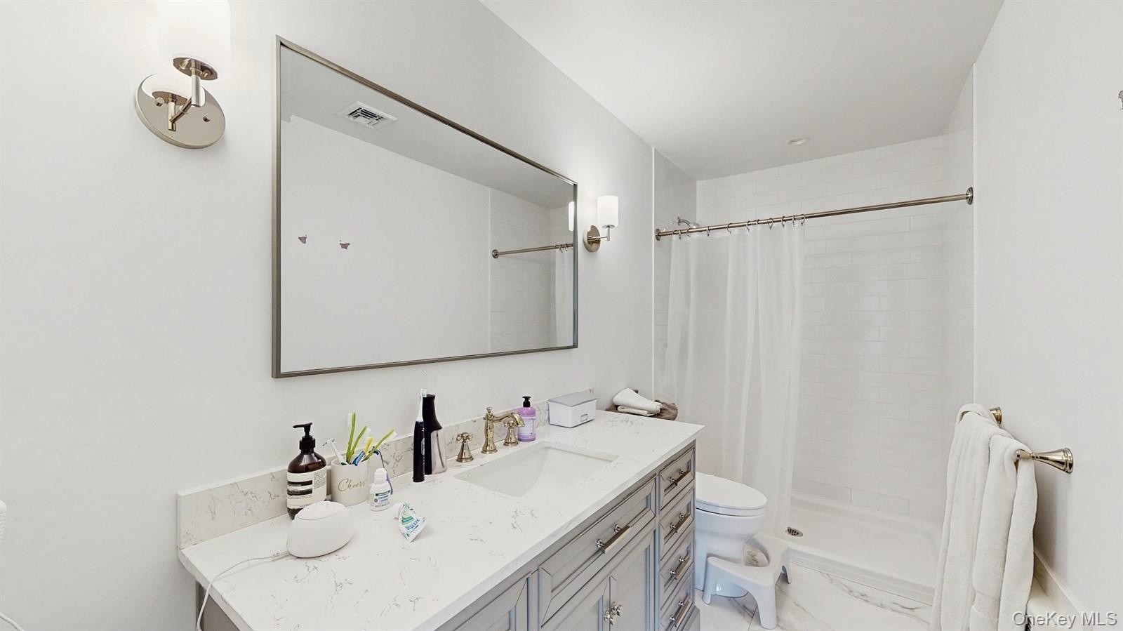 Full bathroom featuring visible vents, toilet, tiled shower, and vanity