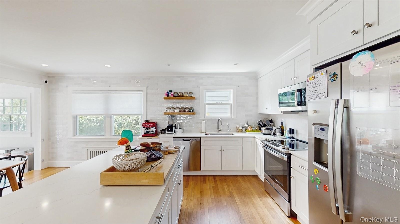 Kitchen with a sink, white cabinets, appliances with stainless steel finishes, and a healthy amount of sunlight