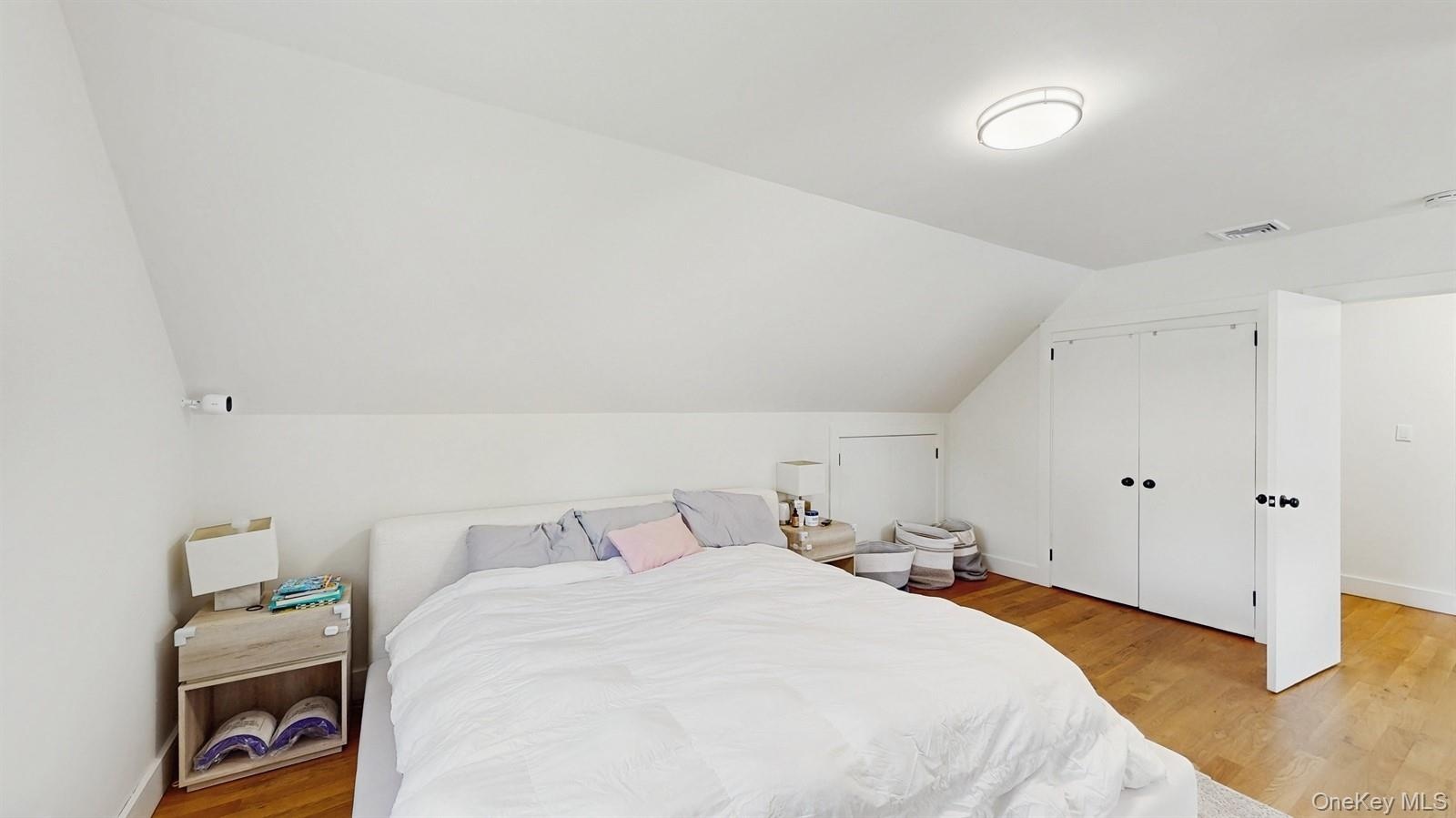 Bedroom with visible vents, baseboards, a closet, light wood-style floors, and vaulted ceiling