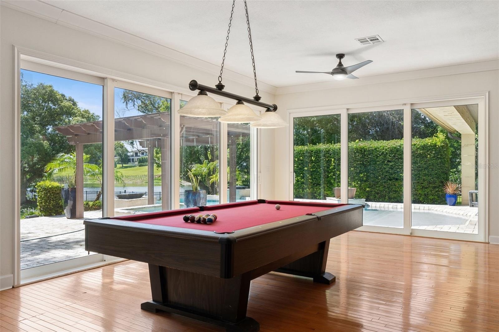 Game Room with view of the Pool and Lake.  Beautiful natural wood floor.  Sliding Energy effcient doors for the open air experience