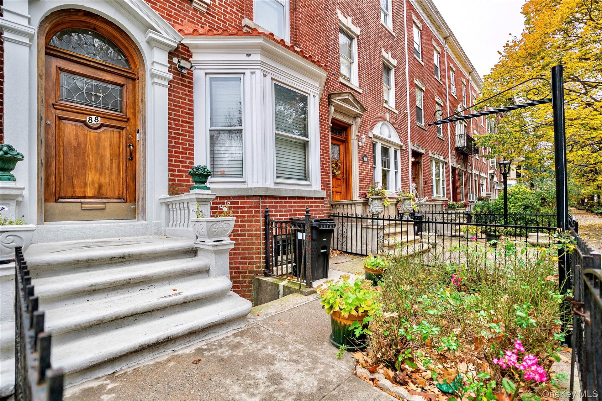 Brick facade row house featuring a paneled wood-finish entry door with leaded glass, an arched transom, and white trim