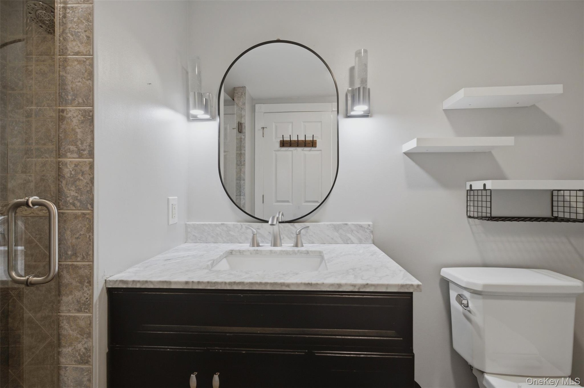 Bathroom vanity with a white marble countertop, undermount sink, and dark wood-finish cabinetry