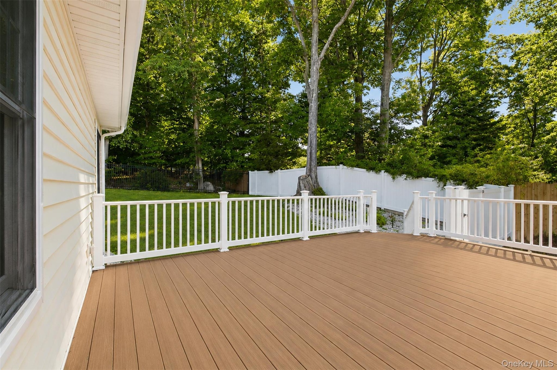 Expansive outdoor deck featuring wood-finish flooring and white railings