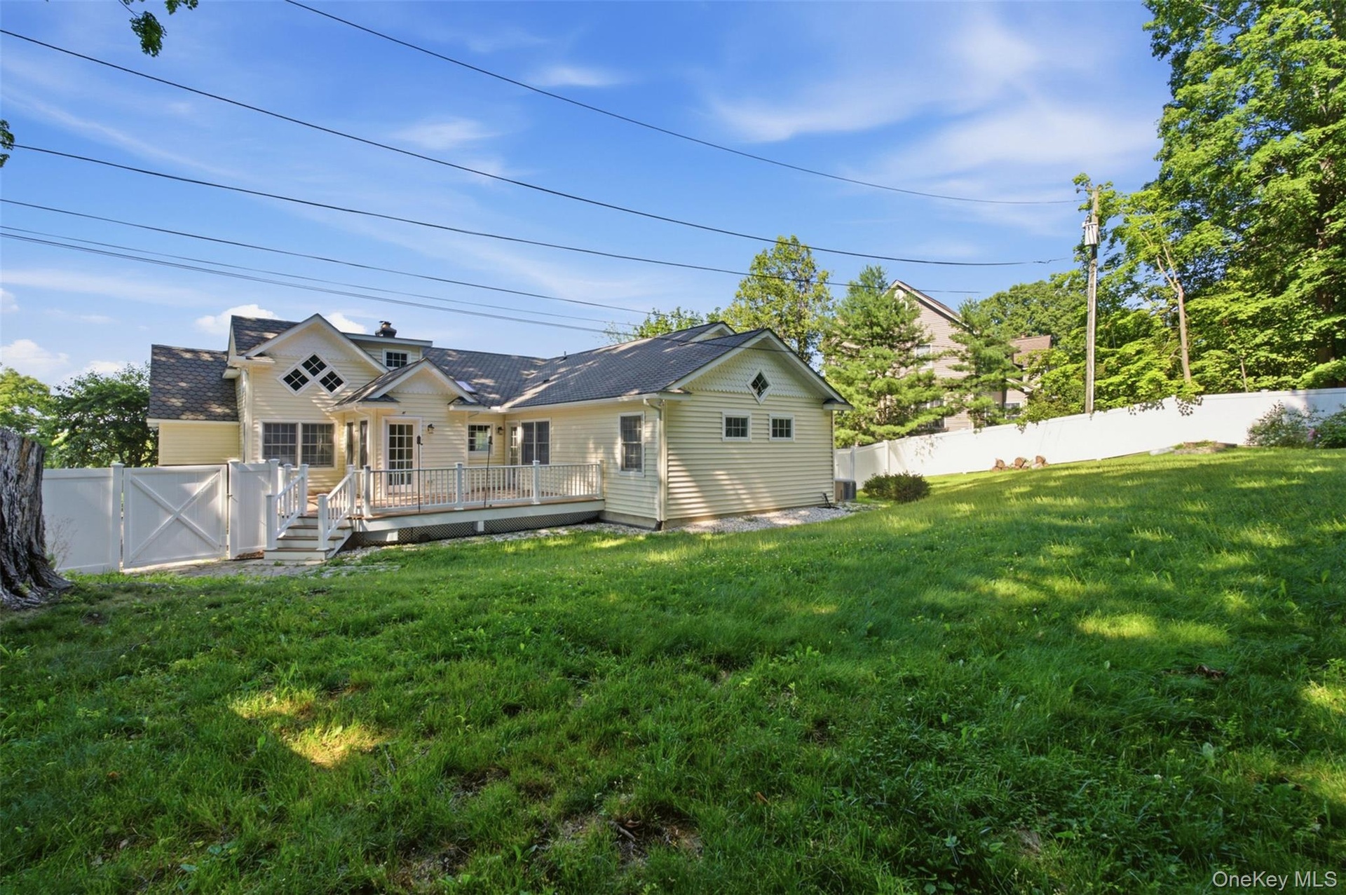 Expansive backyard featuring a manicured lawn, a full-length deck with white railings, and a privacy fence