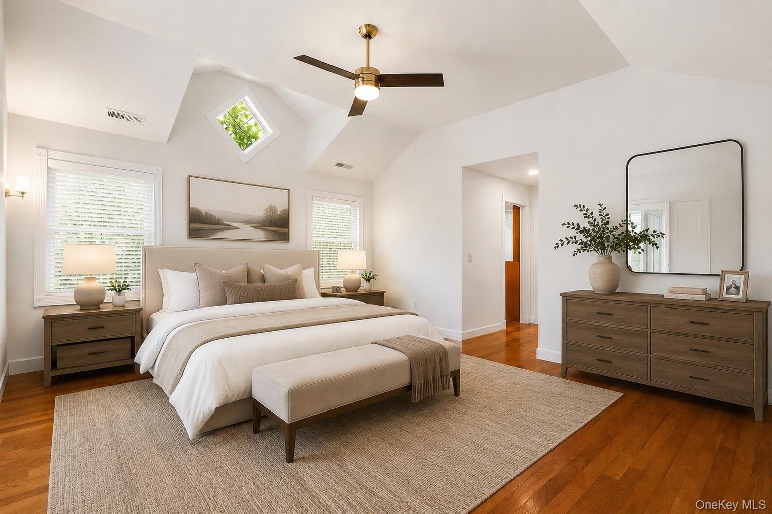 Spacious bedroom featuring vaulted ceilings, wood-finish flooring, and multiple windows including a prominent diamond-shaped window