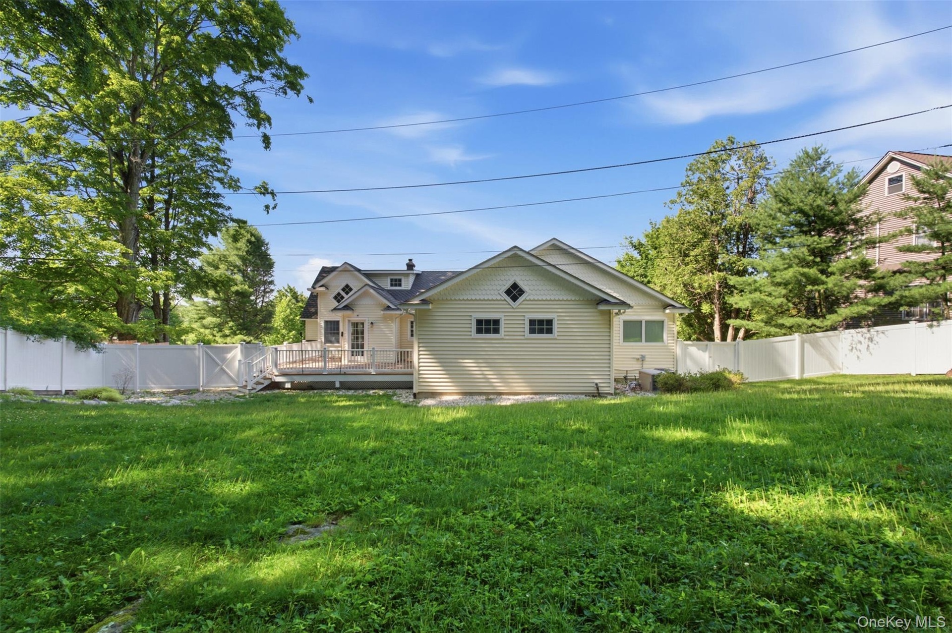 Expansive lawn area featuring a white privacy fence