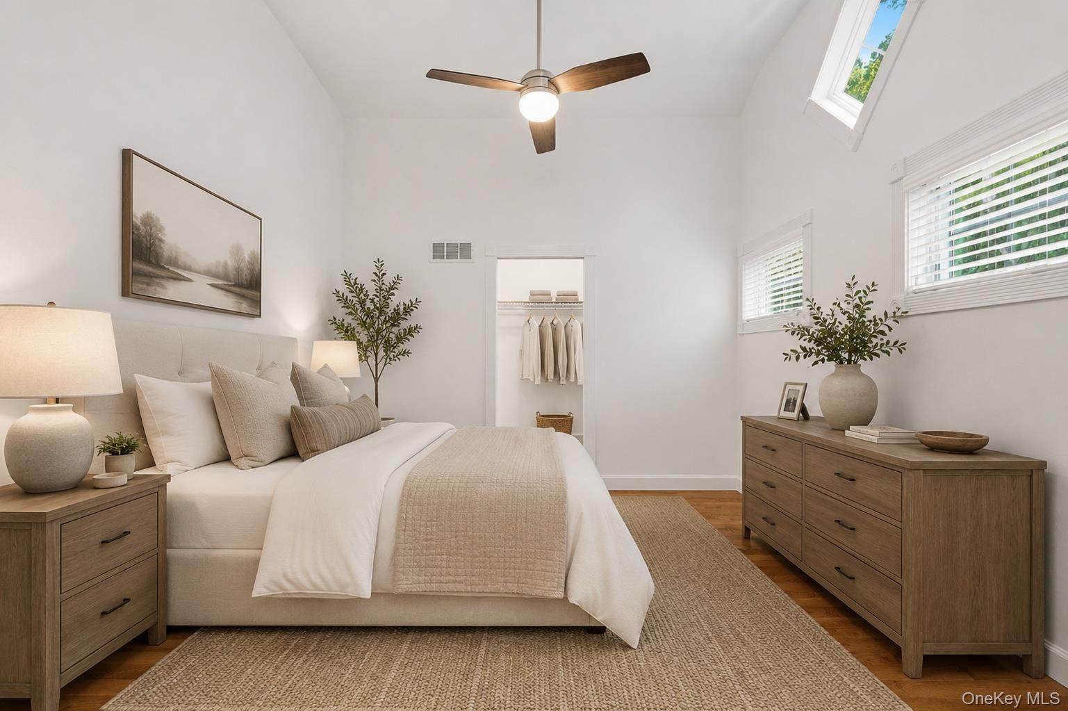 Vaulted ceiling bedroom 2 on the first level  featuring wood-finish flooring, a ceiling fan with integrated lighting, and multiple windows including t