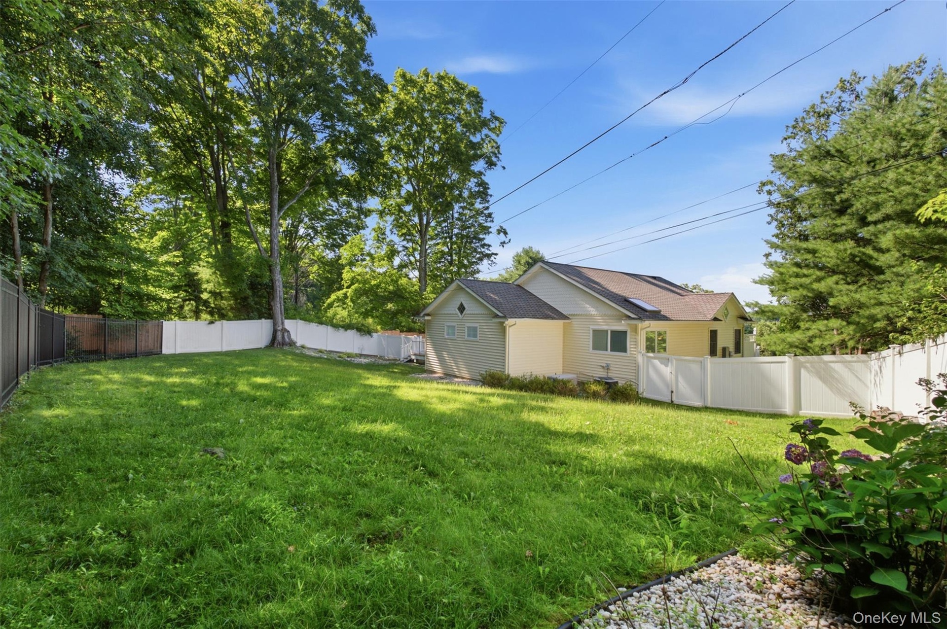 Spacious lawn area framed by a white privacy fence and mature trees
