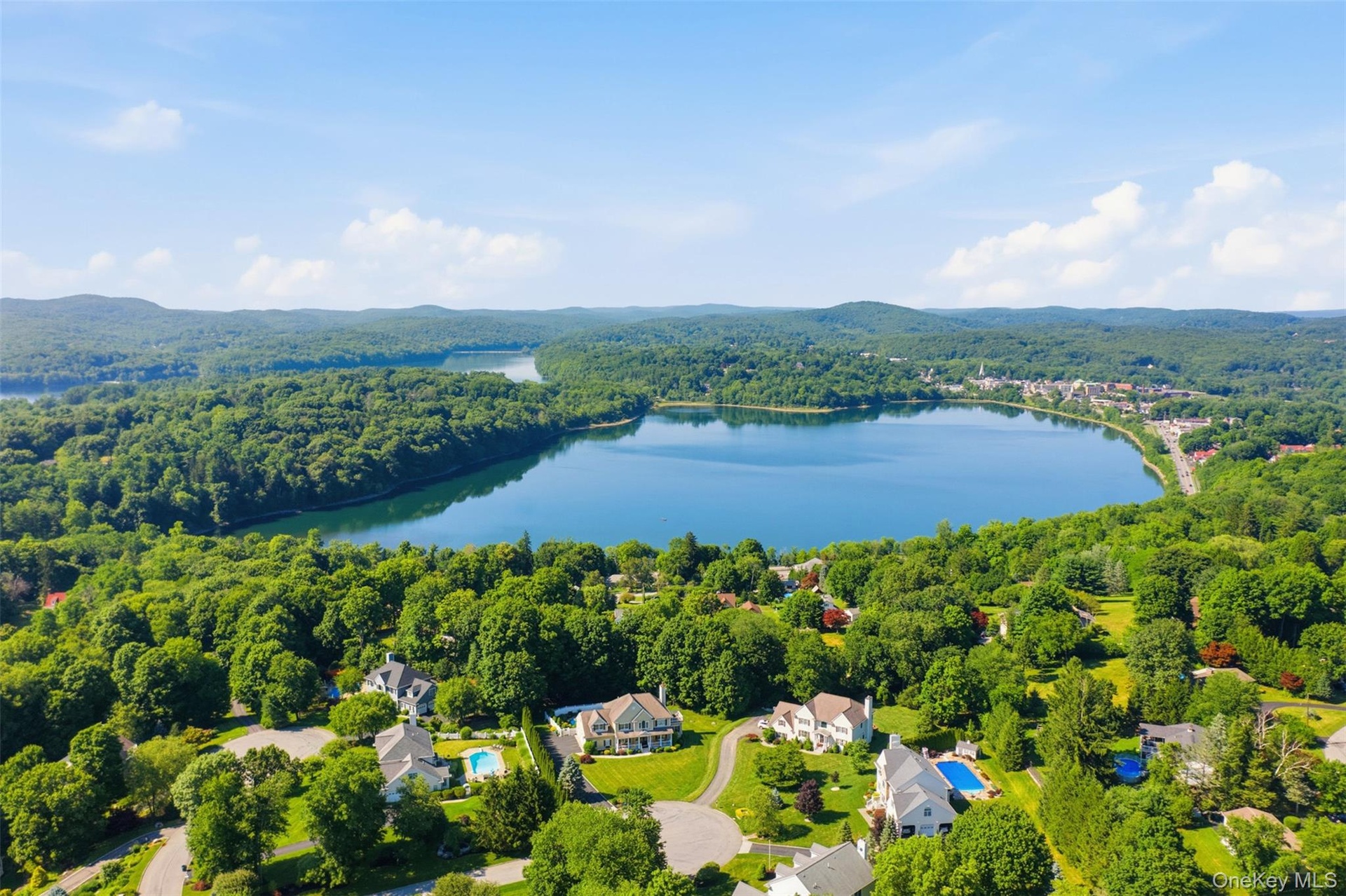 Aerial perspective showcasing a large body of water surrounded by expansive green landscapes and residential properties