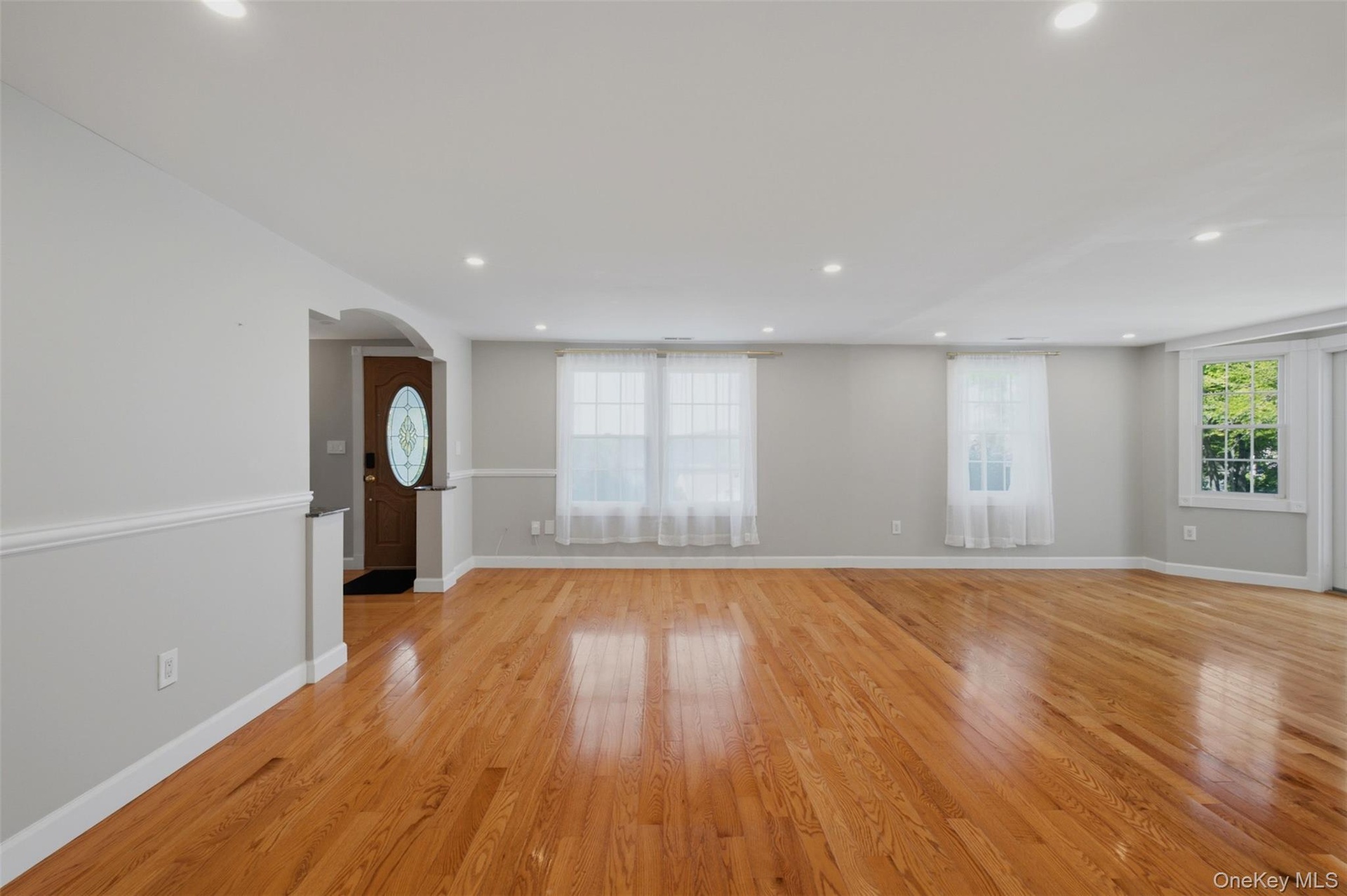 Spacious family room area featuring wood-finish flooring, recessed lighting, and a neutral color palette