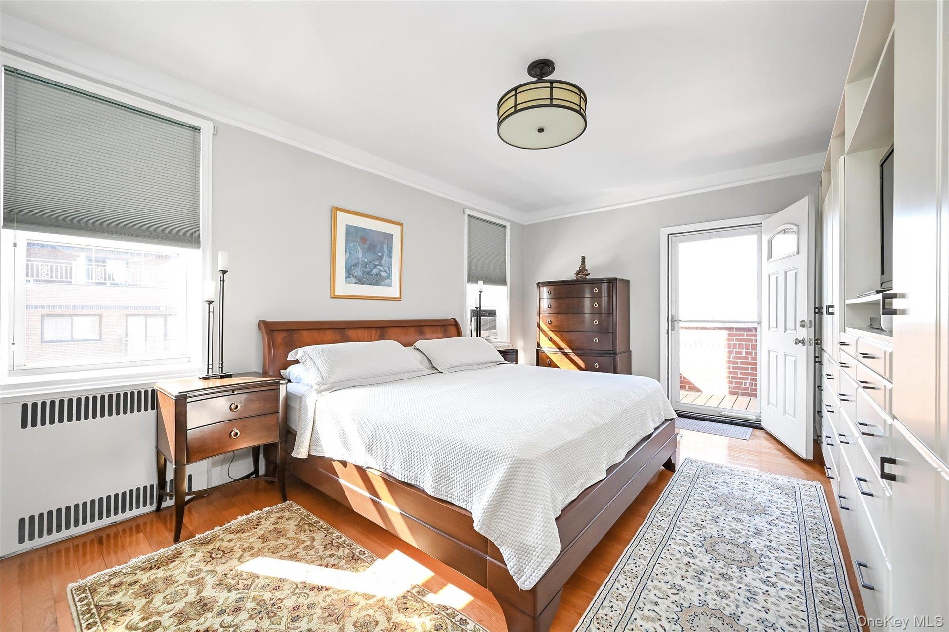 Full view of Primary bedroom with balcony entrance. Beautifully renovated hardwood floors