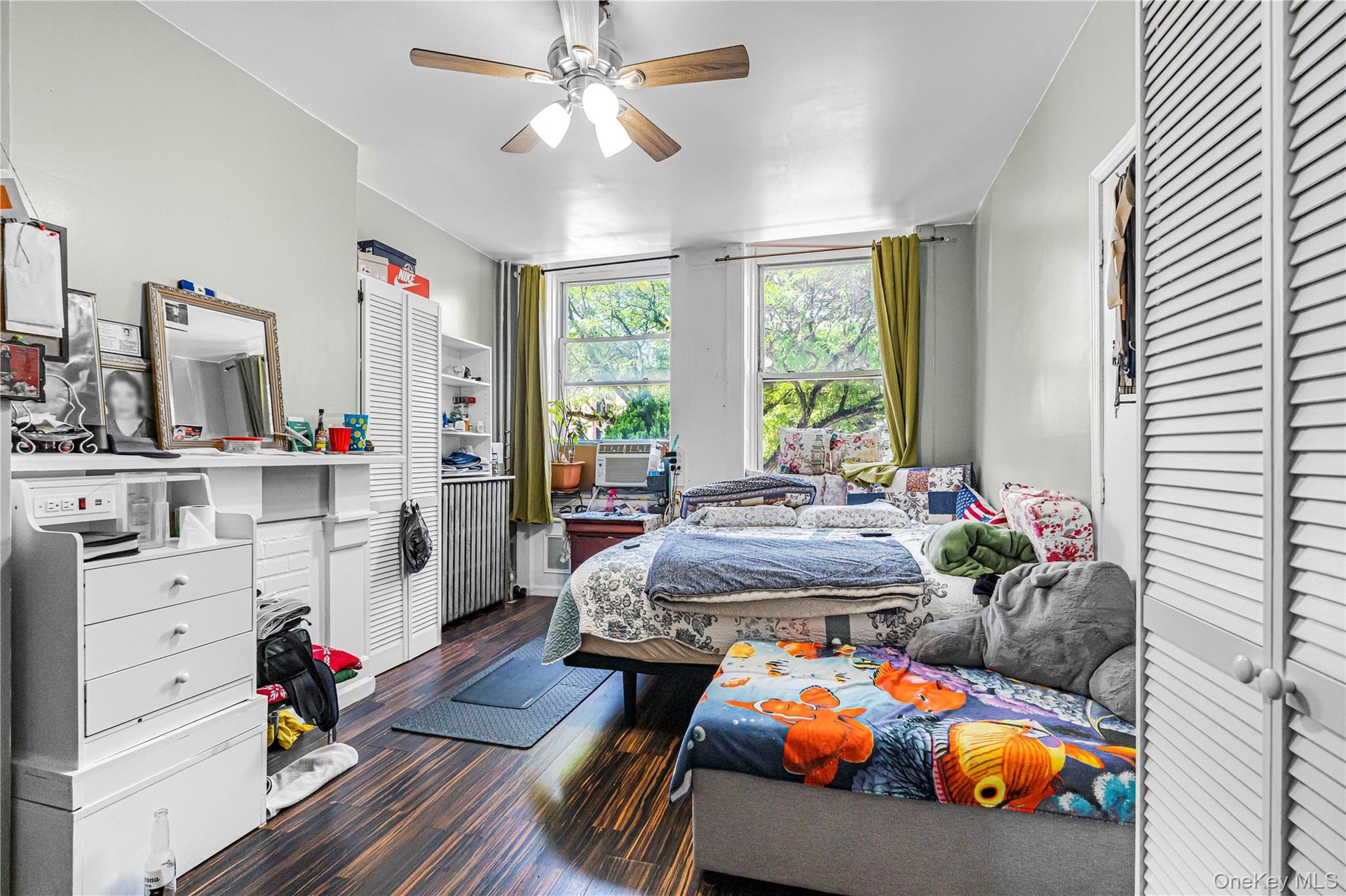 Bright interior space featuring wood-finish flooring, a ceiling fan with light fixture, and two large windows