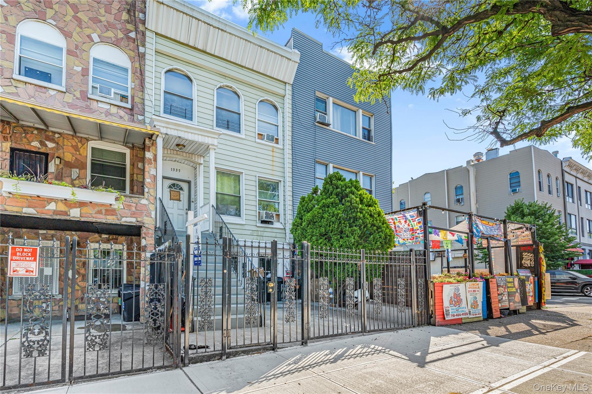 Light-colored facade with prominent entry staircase and wrought iron fencing