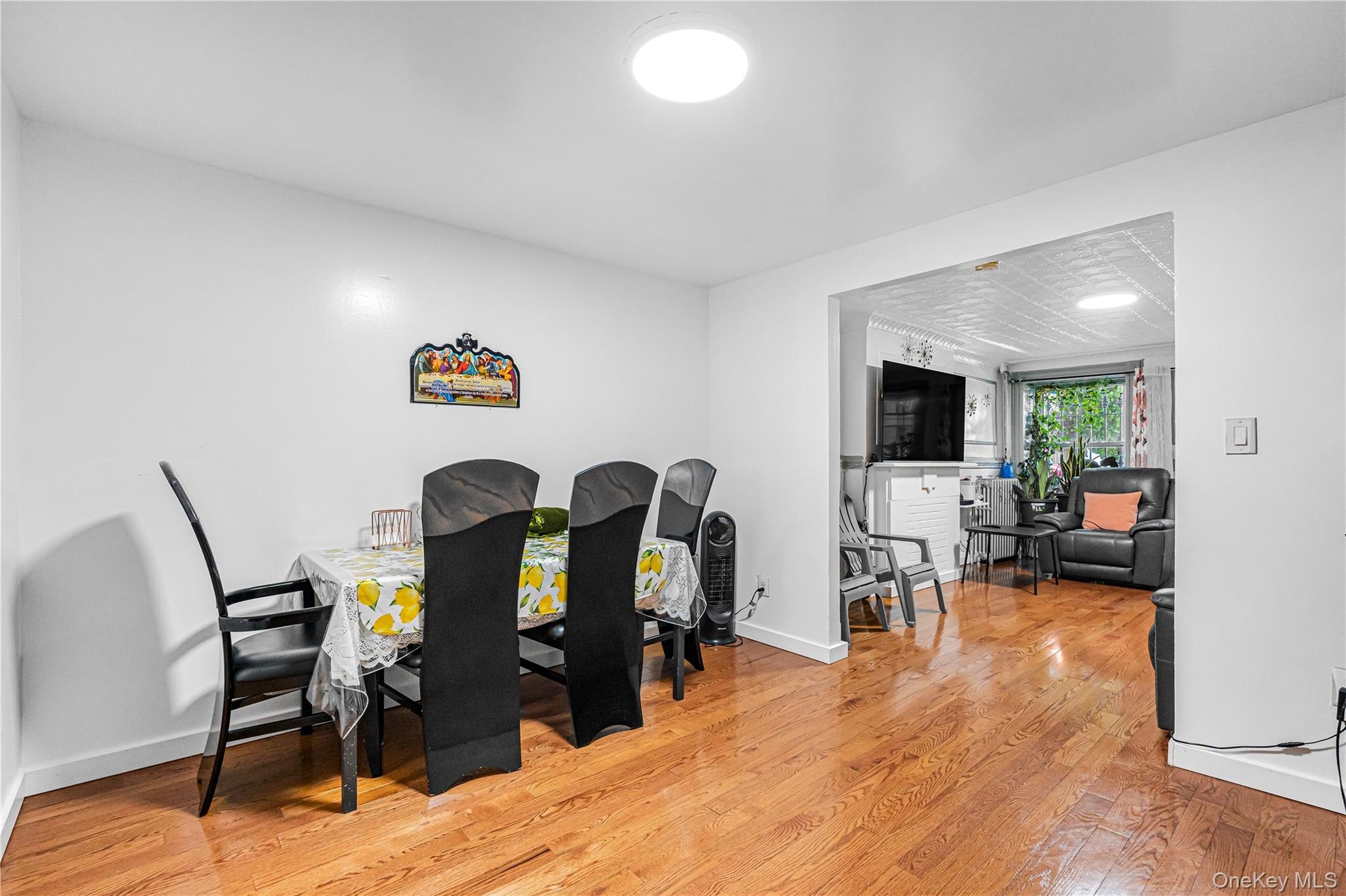 Dining area featuring wood-finish flooring, white walls, and an open entryway to an additional living space