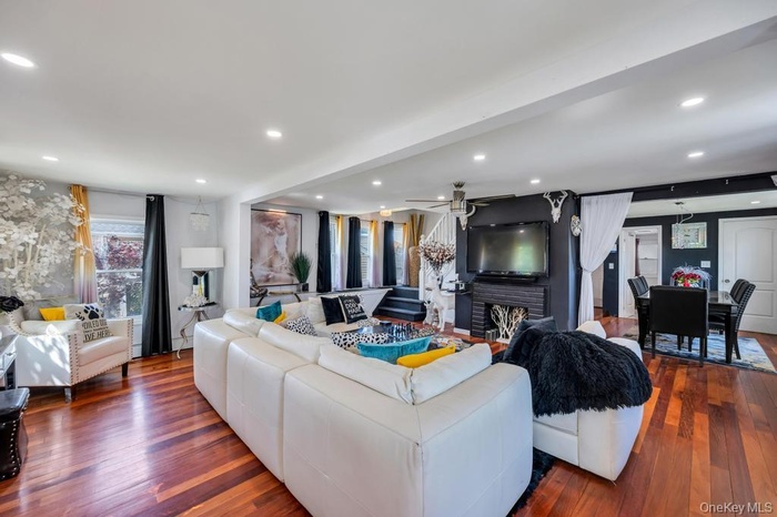 Open-concept living space featuring wood-finish flooring, recessed lighting, and a dark accent wall with a fireplace