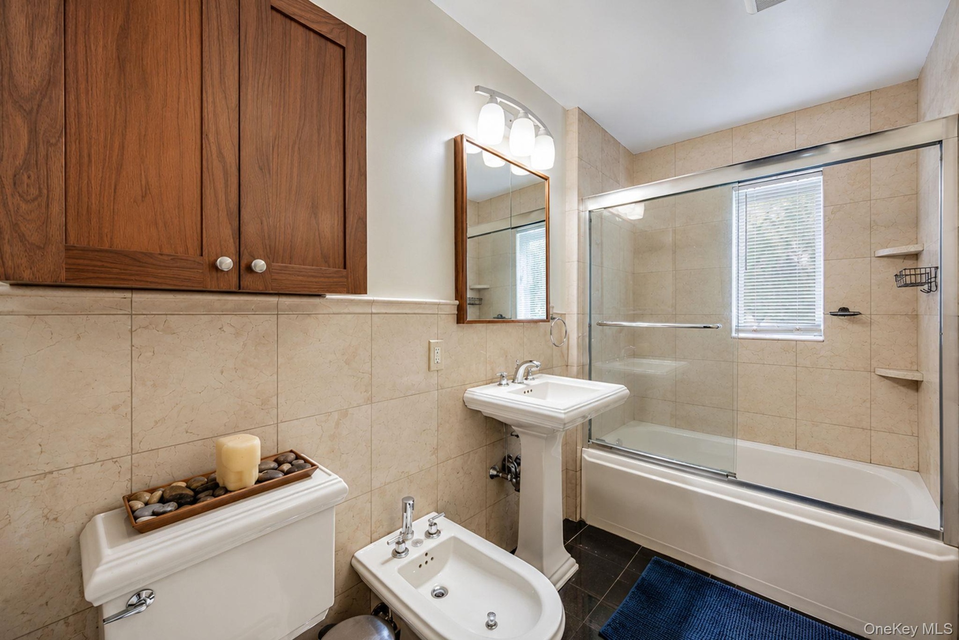 Bathroom featuring a pedestal sink, white toilet, and bidet