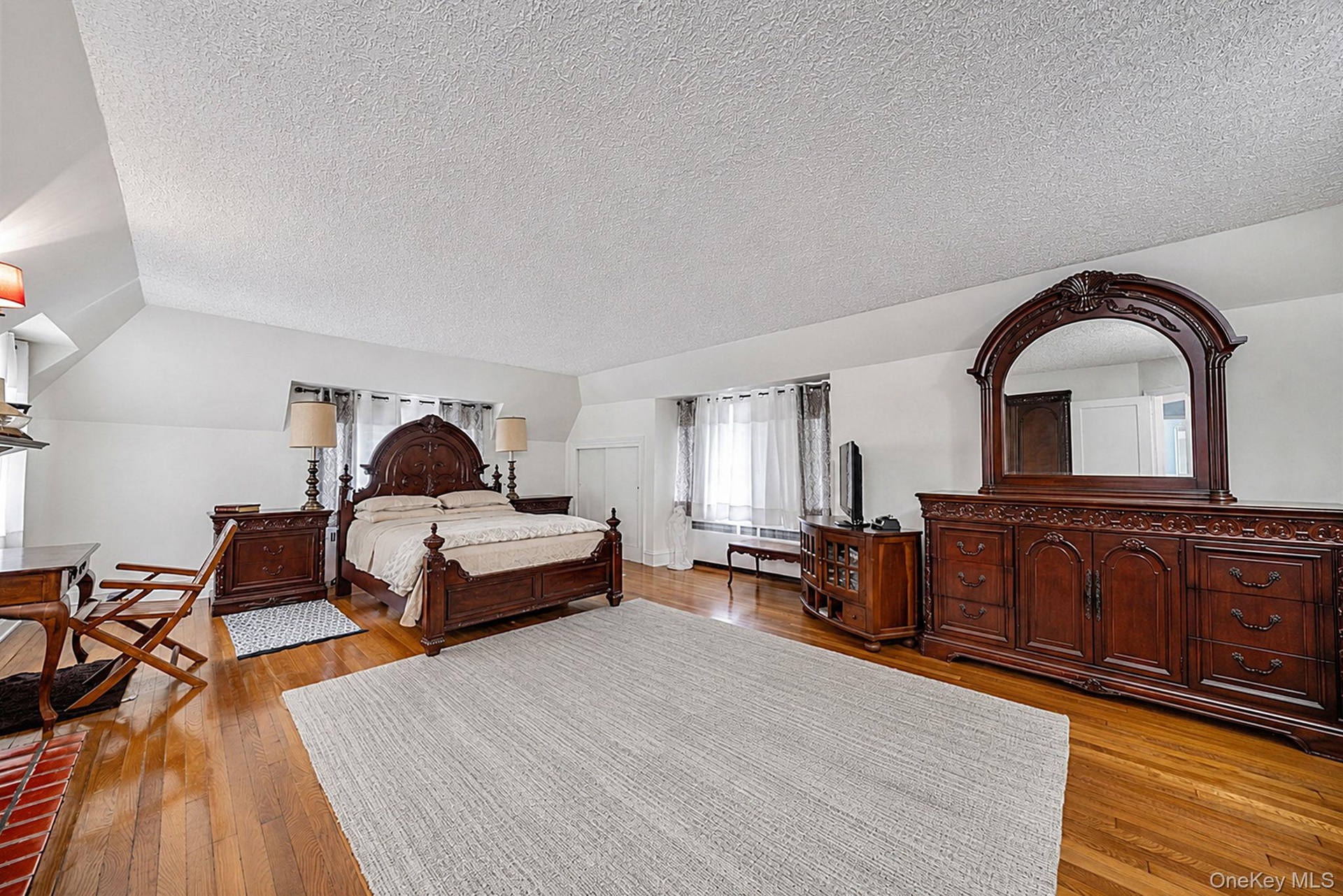 Spacious room featuring wood-finish flooring, white walls, and a sloped ceiling
