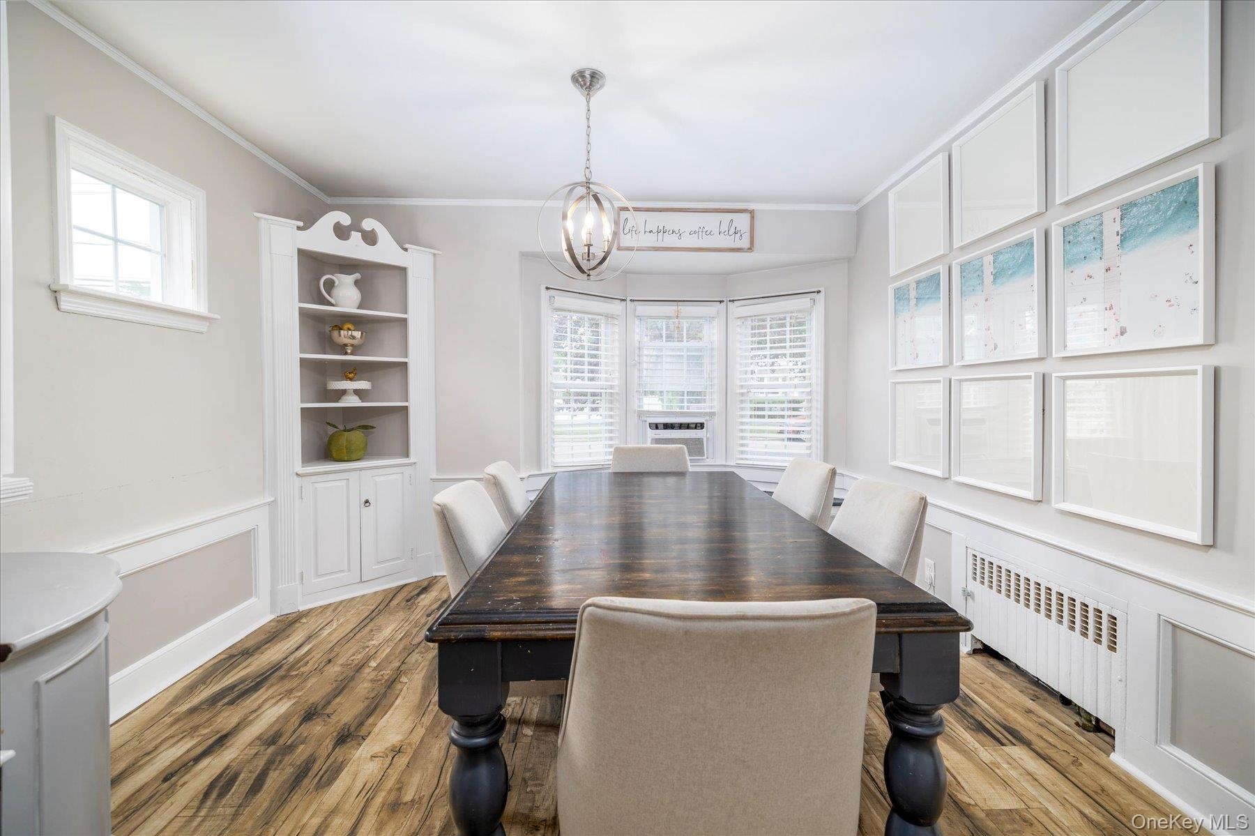 Dining space featuring wood-finish flooring, a built-in corner hutch and a bay window.
