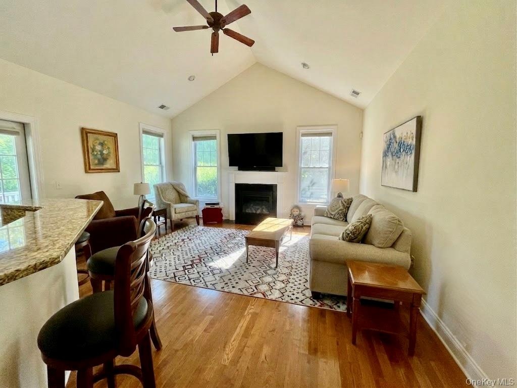 Spacious living room featuring a vaulted ceiling and wood-finish flooring and gas fireplace