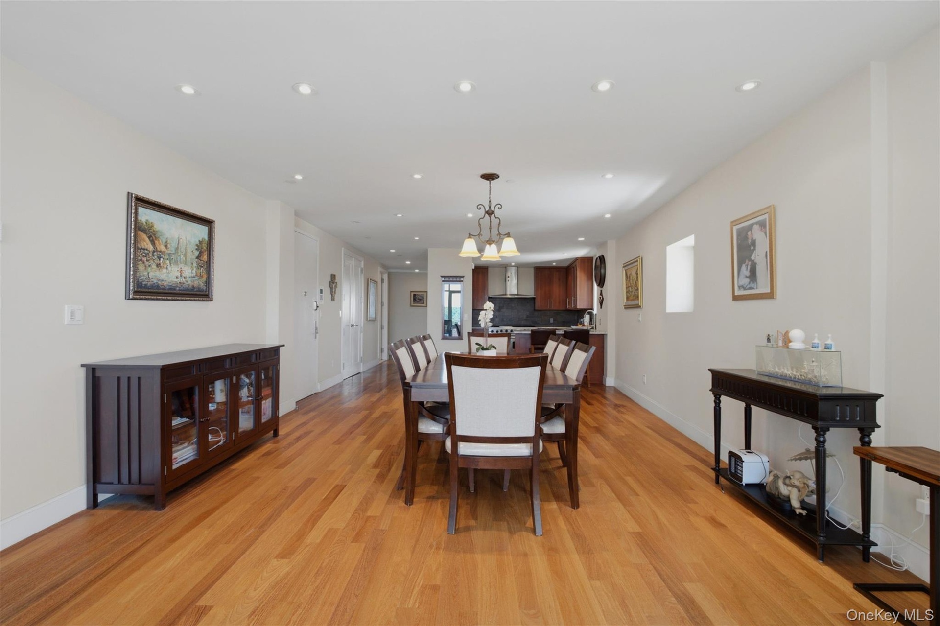 Open-concept dining area featuring wood-finish flooring, recessed lighting, and a chandelier