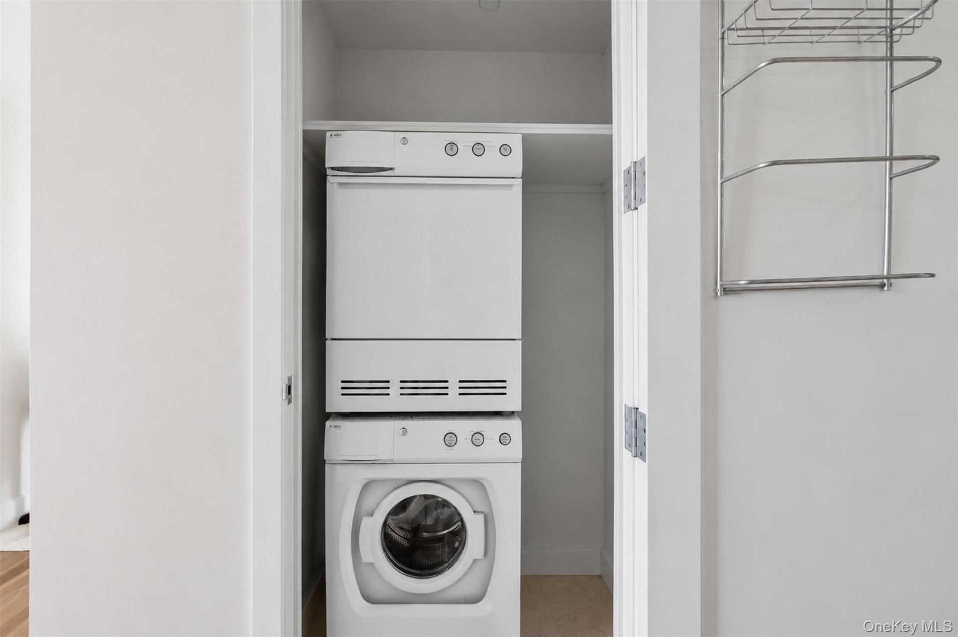Dedicated laundry closet featuring a stacked white washer and dryer unit